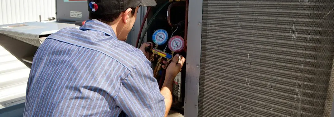 HVAC technician servicing a condenser unit in Westphalia